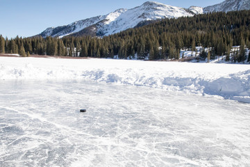 Fototapeta premium Puck on a small rink - Pond hockey on Andrew's lake in Colorado near Silverton