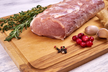 A piece of meat on a wooden Board with a sprig of rosemary and garlic dolkami