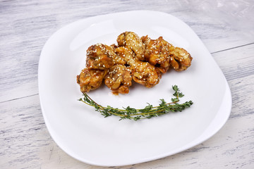 Pieces of chicken on a white plate sprinkled with sesame seeds