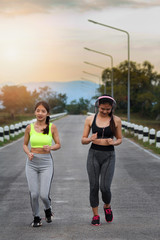 Happy and beautiful women joggers running on road. Fitness and workout wellness concept.