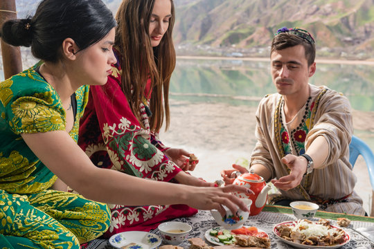 Group of Tajik women and men eating together in lakeside restaurant