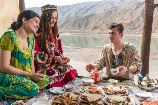 Group of Tajik women and men eating together in lakeside restaurant