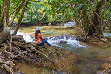 woman sit on root tree and look water fall view
