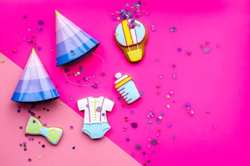 Fototapeten Celebrate birthday of a little baby. Cookies in shape of accesssories for child and party hats on pink background top view copy space © 9dreamstudio