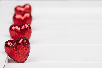 Red glitter hearts on a white wooden background