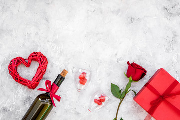 Celebrate Valentine's day. Wine, glasses, red rose, heart sign, gift box on grey background top view copy space