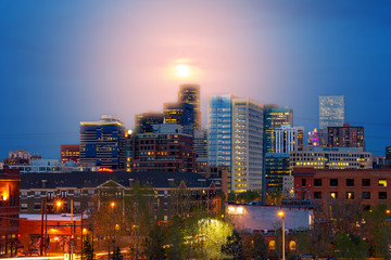 Denver Colorado colorful night skyline with glowing full moon above the downtown skyscrapers at dusk