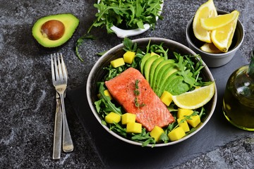 Salmon and mango salad on the dark background. Top view food