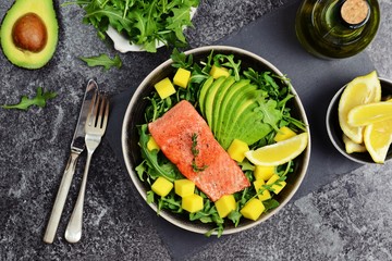 Salmon and mango salad on the dark background. Top view food