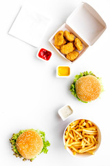 Fast food. Chiken nuggets, burgers and french fries on white background top view space for text