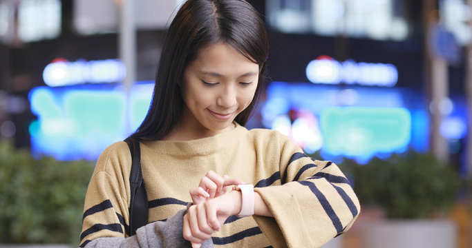 Young woman use of smart watch for check next time schedule appointment in the city at night