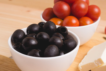 Greek salad with vegetables, feta cheese, black olives in process. Wooden background . Top view