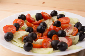 Greek salad with vegetables, feta cheese, black olives in process. Wooden background . Top view