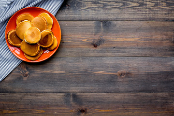 Pile of hot homemade pancakes on bright plate. Dark wooden background top view copy space
