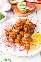 Chicken kebab with a lemon and onion on a wooden background.