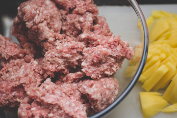 Sliced potato for soup and meat stuffing for making meatballs. Soup with meatballs and pasta prepear in process.