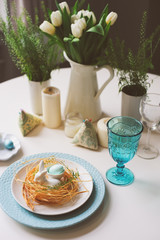 easter festive table with dining place decorated with nest, bunny and eggs