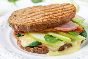 Sandwich with ham, brie cheese or Camembert, spinach, Apple and mustard. Gourmet Breakfast closeup. Selective focus
