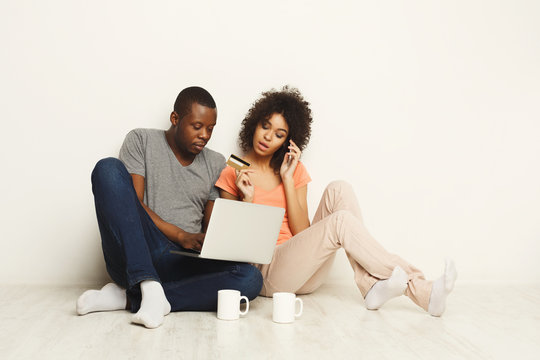 Happy african-american couple shopping online on laptop