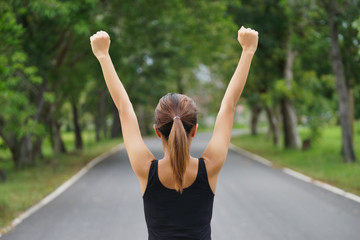 Successful man raising arms after cross track running on summer sunset. Fitness female athlete with arms up celebrating success and goals after sport exercising and working out.