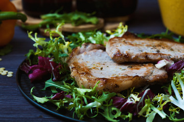 fried meat with salad, herbs, pepper on a dark wooden background. Background for the postcard.