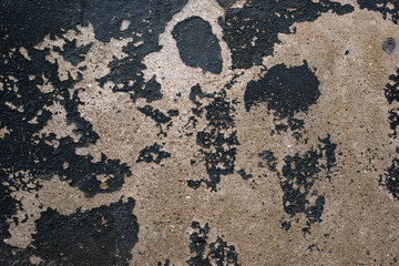 Abblätternde Wandfarbe / Die Nahaufnahme von abblätternder dunkler Wandfarbe auf einer Mauer mit Körnung.