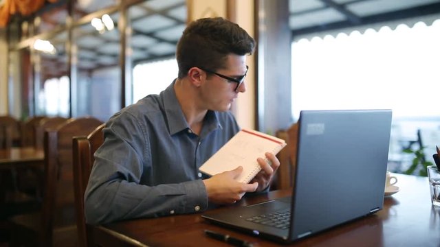 Businessteam. Businessman listening to manager in a video conference and talks about project implementation showing notepad to a laptop front web camera. Telecommuting business concept.