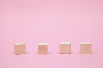 Four wooden cubes on pink background
