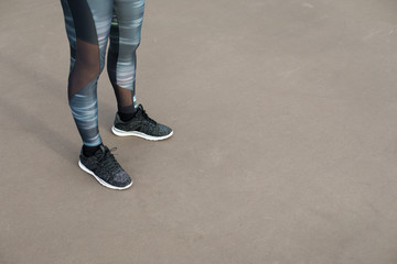 Urban fitness workout concept. Close up of female athlete running shoes and sport fashion leggings.