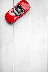 Small toy car on a white wooden background.