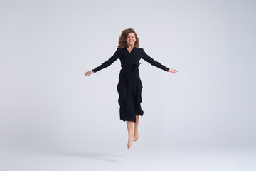 Cheerful young woman jumping up in the air