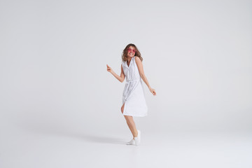 Attractive girl in dress dancing in studio on white background