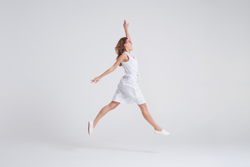 Pretty girl in dress jumping isolated over background