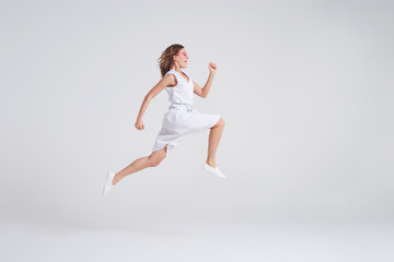 Fototapeta na wymiar Crazy joyful girl in summer dress jumping isolated over background