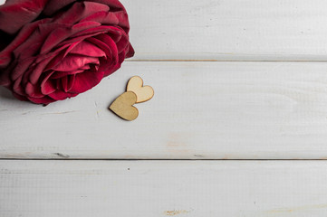 Wooden hearts and red rose on white boards background