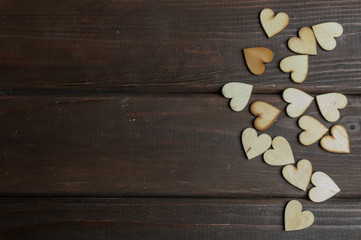 Little wooden hearts on brown wooden background