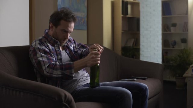 Male opening bottle of beer with fork, drinking with pleasure, alcoholic
