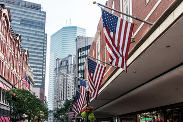 Boston, MA USA Shopping Mall Store front with american flags waving with skyscrapers in the background skyline