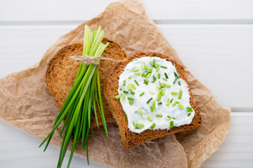 Bowl of cream cheese with green onions, dip sauce on wooden table.