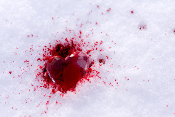 crystal heart lies on the snow in the blood, drops of blood on the snow, copy space, .close up, selective focus