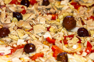 cooking homemade pizza with peppers, plums, ham, sausage, cheese and spices, closeup