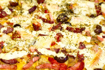 homemade pizza with peppers, plums, ham, sausage, cheese and spices, closeup