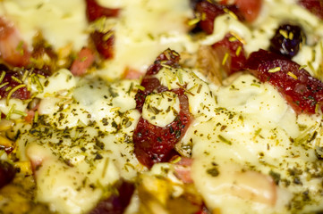 homemade pizza with peppers, plums, ham, sausage, cheese and spices, closeup