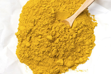 fresh arabic turmeric (curcuma) in white paper with wooden spoon