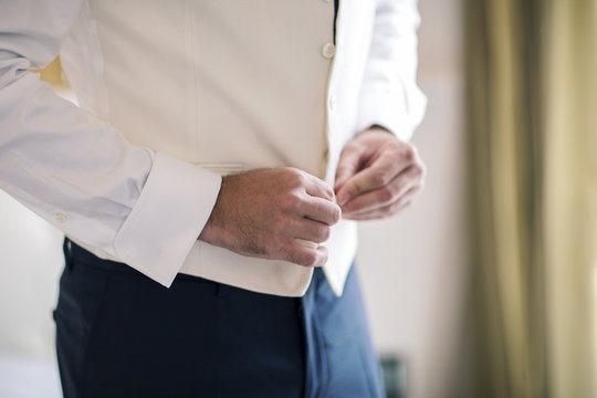 Close-up of a man buttoning a waistcoat