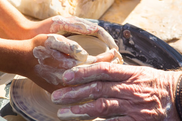 adult hand fed baby's hands to work with a potter's wheel