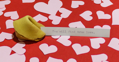 "You will find true love" message in fortune cookie on red background covered with harts