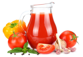 Tomato juice in glass jug with tomato, garlic, spices, and basil isolated on white background