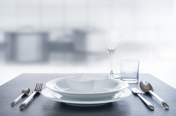 Besteck und Geschirr für Menü auf spiegeldem Granittisch in Küche, Hintergrund