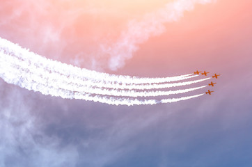 Group of white fighter jet airplane with a trace of white smoke against a blue sky.